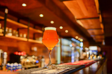 Beer in a tall glass with on wooden table top in a bar. Eating out concept.
