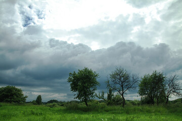 Thunderous epic clouds in a field near the old garden. Stock photo background with heaven.