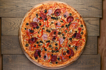 Flat lay photograph of tasty italian pizza on rustic wood. Pepperoni, cheese and peppers. Delicious food.