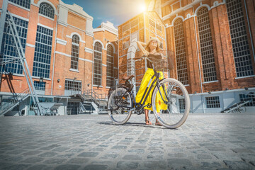 Happy traveler woman with her bicycle rides in city and looking on streets view in sunny summer day. Freedom, Travel, Journey, concept.