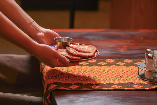 Potato pancakes dranik with sour cream, traditional Ukrainian dish. Waiter in traditional uniform serving dranyki.
