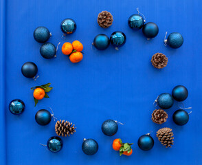 Christmas balls, layout for the New Year and Christmas. Tangerines, pine cones and brown paper. Flat lay, top view, copy space. Blue background. 