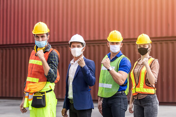 Teamwork engineer technician and foreman and partner wearing protection face mask and safety yellow helmet in cargo container shipping area, worker successful.