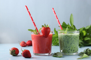 Two healthy detox smoothie with fresh strawberries, spinach, mint and yogurt in glasses on light blue background with fresh ingredients, Diet and weight loss control concept, Horizontal format