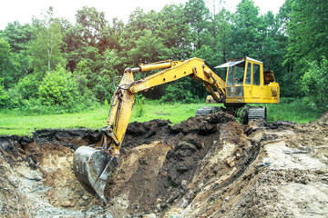 An excavator digs a large trench for building a house. A tractor digs a large lake that is already...