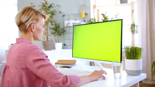 Businesswoman with computer working indoors in office, keyable screen.
