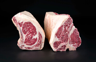 Raw dry aged wagyu porterhouse and cote de boeuf beef block as closeup on black background with...