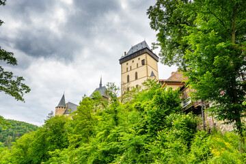Fototapeta premium Famous medieval gothic castle Karlstejn on top of the hill. Beautiful stronghold is built by king Charles IV. Historical national heritage of Czech Republic is placed near Prague city. Cloudy weather