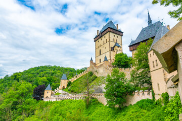 Fototapeta na wymiar Famous medieval gothic castle Karlstejn on top of the hill. Beautiful stronghold is built by king Charles IV. Historical national heritage of Czech Republic is placed near Prague city. Cloudy weather