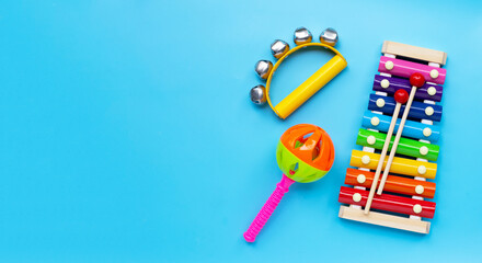 Hand bells musical instrument for ringing with colorful xylophone and baby rattle on blue background.