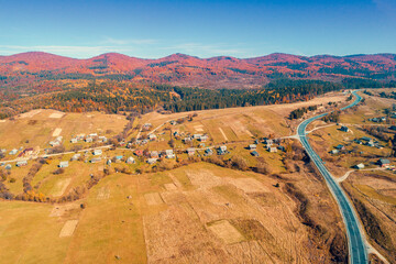 Panoramic aerial view of the mountain highway and village in autumn. Beautiful skyview countryside landscape. Carpathian mountains. Ukraine