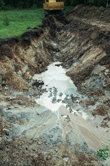 An excavator digs a large trench for building a house. A tractor digs a large lake that is already gaining water. Stock background for design