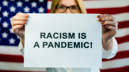 Woman holds poster Racism is Pandemic on american flag background. Human Rights Demonstration