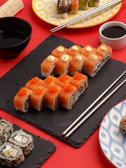 Sushi rolls on colored plates on a red background. A look from above.