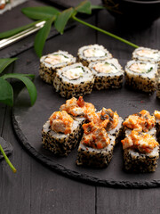 Sushi rolls on colored plates on a black background. A look from above.