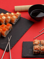 Sushi rolls on colored plates on a red background. A look from above.