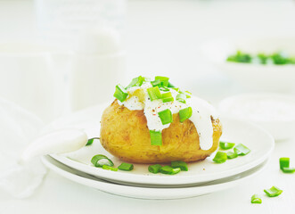 Baked potatoes with cheese, served with sour cream and onions. Selective focus