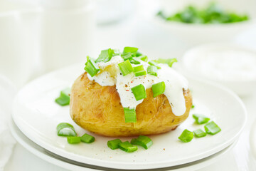 Baked potatoes with cheese, served with sour cream and onions. Selective focus