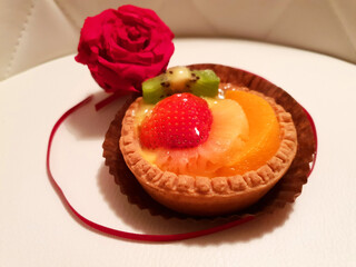 Fruit cupcake with strawberry and red rose on white background.