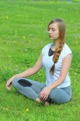 Young woman of European appearance does yoga in summer nature