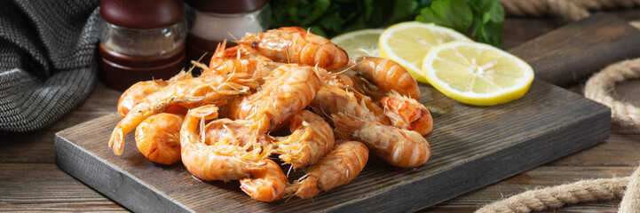 Shrimp on a wooden Board on a brown wooden table. Shrimp shrimps visor. Ecological seafood. Banner