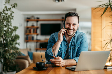 Portrait of a happy casual man talking on smart phone at home office.