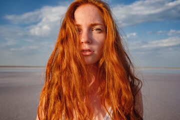 Beautiful young lady with long healthy red hair and cute dress