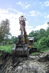 Fototapeta na wymiar An excavator digs a large trench for building a house. A tractor digs a large lake that is already gaining water. Stock background for design