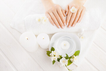 beautiful french manicure with jasmine, candle and towel on the white wooden table. spa