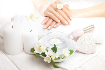 Obraz na płótnie Canvas beautiful french manicure with jasmine, candle and towel on the white wooden table. spa