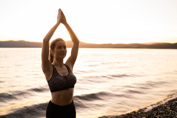 Fototapeta na wymiar Sunrise meditation. Silhouette of a woman doing yoga exercise in the morning