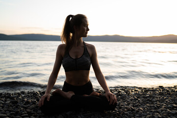 Fototapeta na wymiar Beautiful girl in a yoga pose on the lake. Lotus position