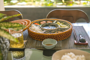 rice bowl with rattan, inside is traditional Vietnamese lunch, rice, soup, salty food. The scene is...