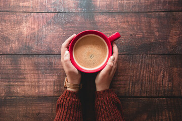 Frauenhände halten eine rote Tasse mit Kaffee - Holz Hintergrund