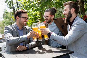 Young businessmen are drinking beer, talking and smiling while resting at the pub