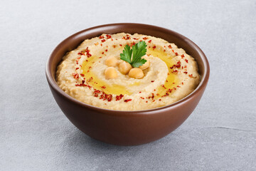 Chickpeas hummus with olive oil, paprika and parsley on a gray background.
