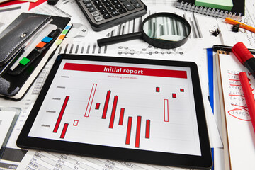 Top view of office employee's desk - work with tablet pc computer and financial reports, analysis and accounting, tables and graphs, various office items for bookkeeping