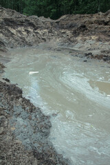 Dug hole in the ground is filled with water to the level. Swamp from the element that destroyed human activity. Stock abstract background