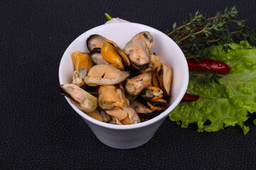 Pickled mussels in the bowl served pepper, garlic and salad