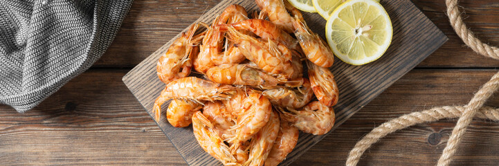 Shrimp on a wooden Board on a brown wooden table. Shrimp shrimps visor. Ecological seafood. Top view with space for text. Banner	