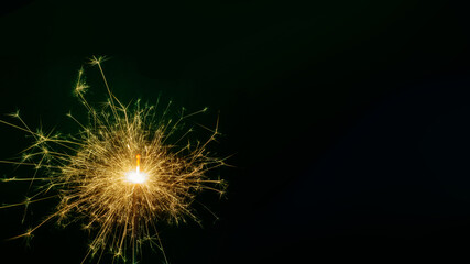 New Year single colored sparkling burning sparkler, salute on black background. Holiday concept background, copy space © Alena