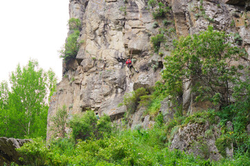 A climber climbs a steep cliff high in the mountains. Eco tourism, travel an active lifestyle.