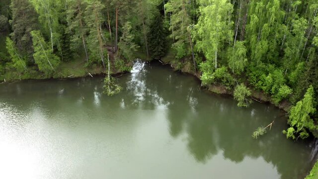 Water in a mountain forest lake with pine trees. Aerial view of lake and green forests. View on the lake between mountain forest. Over crystal clear mountain lake water. Fresh water