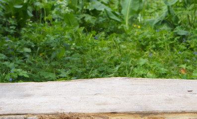 Image of a wooden table made from whole sawn logs in front of a natural blurred natural background. Can be used to showcase or assemble your products.
