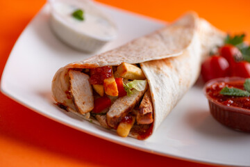 Grilled chicken in sandwich from fresh pita bread with onion and greens on  white plate