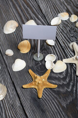 Starfish and shells are scattered on pine boards painted in black and white. Among them is a pointer with a field for an inscription.