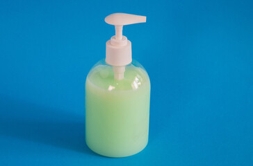 Plastic bottle with green liquid soap on a blue background.