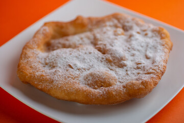 Traditional Transylvanian hungarian pastry, deep fried dough langos  with sugar close up on white plate