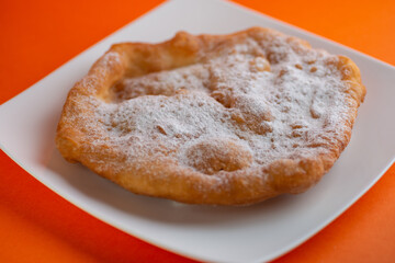 Traditional Transylvanian hungarian pastry, deep fried dough langos  with sugar close up on white plate