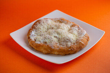 Traditional Transylvanian hungarian pastry, deep fried dough langos close up on restaurant table with cheese, sour cream and garlic.